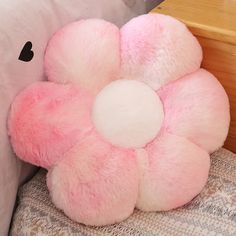 a pink flower shaped pillow sitting on top of a bed