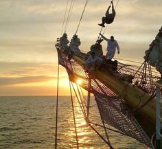 the sun is setting on an old sailing ship