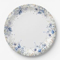 a white plate with blue flowers and leaves on the rim, against a white background