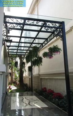 an outdoor covered walkway with potted plants and flowers on the side of the building