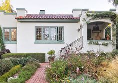 a white house with lots of plants and flowers