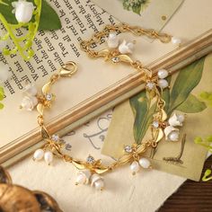 Blossom into style with our Golden Lily of The Valley Bracelet, where floral charm meets golden elegance. This bracelet is a petal-perfect addition to your ensemble, adding a touch of nature's brilliance to your wrist. Let it be a blooming statement piece that reminds you to "grow with grace" and "bloom where you are planted." Flaunt your flower power with this delightful accessory! DETAILS Plating: 18k Gold Materials:   18K Gold on Brass, Cubic Zirconia, Enamel, Pearl Measurements: Length: 6. Luxury Elegant Bracelets With Flower Charm, Gold Flower-shaped Elegant Bracelets, Gold Flower Charm Bracelet Adjustable, Elegant Spring Flower-shaped Bracelets, Elegant Gold Plated Flower-shaped Bracelet, Lily Of The Valley Flowers, Wire Crochet Jewelry, Trendy Fashion Jewelry, Bloom Where You Are Planted