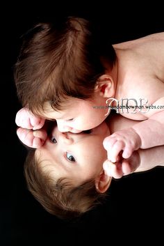 a close up of a baby laying on top of its mother's head and looking at the camera