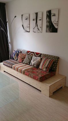 a couch sitting in front of a glass table next to a wall with pictures on it