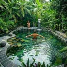 a man swimming in a pool surrounded by lush greenery