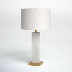 a white lamp with a gold base and a white shade on it's side