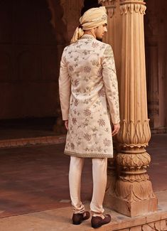 Elevate your traditional style with the luxurious Beige Embroidered Sherwani Set, meticulously crafted from premium silk jacquard. This beige sherwani is adorned with intricate geometric and floral patterns, blending classic artistry with modern elegance. Paired with a matching kurta and pants, it offers a complete look that is both sophisticated and timeless. The ensemble is finished with an embroidered stole in soft pink hues, adding a regal touch to the overall design. Perfect for the groom on their special day, this outfit embodies the essence of tradition and craftsmanship, making it ideal for the modern groom who values both heritage and contemporary style. Composition : Sherwani, Stole, Kurta and Churidar - Silk JacquardCare: Dry Clean Only and Vacuum Storage Delivery : 4-6 weeks as Traditional Beige Unstitched Suit For Formal Occasions, Designer Sherwani With Floral Embroidery For Diwali, Elegant Silk Sherwani With Naqshi Detailing, Designer Floral Embroidered Sherwani For Diwali, Designer Floral Embroidery Sherwani For Diwali, Traditional Drape Sherwani With Floral Embroidery For Diwali, Designer Sherwani With Resham Embroidery In Jamawar, Designer Sherwani With Floral Embroidery For Eid, Traditional Sherwani With Floral Embroidery For Festivals