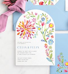 the wedding stationery is decorated with watercolors and paper flowers on blue envelopes