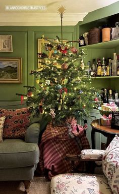 a small christmas tree in the corner of a living room with green walls and furniture