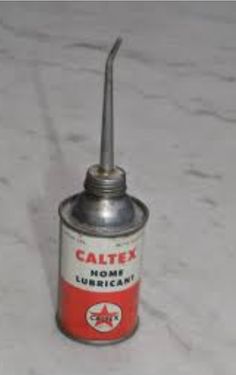 an old tin can sitting on top of a white surface with a metal tip sticking out of it