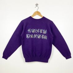 90s South Dakota Crewneck Sweatshirt Print Logo Purple Color Women's S - Made in Mexico  Materials : Cotton, Polyester  - Tag Reads : Women's S Kindly see the actual measurements (All measurements were taken lying flat) - Actual size manual measurements * Width (Armpit to armpit) : 19 inches * Length (Shoulder to end of garment) : 24 inches * Sleeve length : 21 inches - Condition : * Good condition 8/10 (80%) * Minor stain refer picture * Free from tear and major defect - Shipping : * DHL Express/FedEx Express = 3-6 business day arrived * Please PROVIDE your PHONE/CONTACT NUMBER for SHIPPING/DELIVERY purpose DON'T FORGET TO VISIT MY SHOP FOR MORE GREAT STUFF, THANK YOU. Purple 90s Style Tops For Fall, Purple 90s Style Top For Fall, Vintage Purple Sweatshirt For Fall, Purple Vintage Sweatshirt For Fall, Retro Long Sleeve Purple Sweatshirt, Retro Purple Long Sleeve Sweatshirt, 90s Style Cotton Sweater, 90s Style Relaxed Fit Cotton Sweater, 90s Relaxed Fit Cotton Sweater