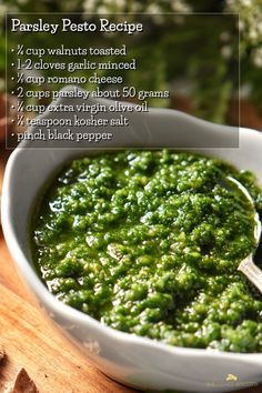 a white bowl filled with pesto on top of a wooden table