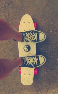 two feet standing on top of a skateboard with white and black shoes in front of them