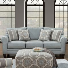 a living room filled with lots of windows next to a blue couch and footstool