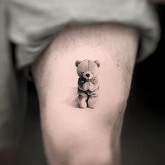 a small teddy bear tattoo on the right side of the leg, it is black and white