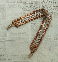 a bracelet made out of metal beads on top of a piece of paper with writing in the background