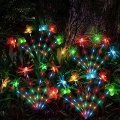 colorful lights in the shape of flowers are lit up at night near a large tree