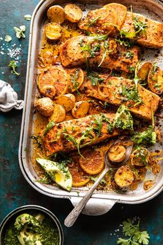 a pan filled with chicken, potatoes and broccoli on top of a table