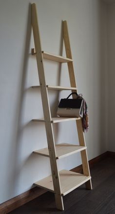 a wooden ladder leaning against a wall with a purse on it's bottom shelf