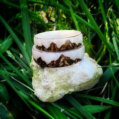 two bracelets sitting on top of a rock in the middle of some green grass