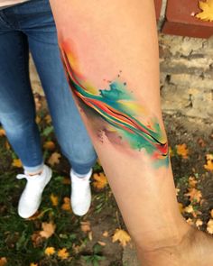 two people standing next to each other with colorful tattoos on their arms and legs,