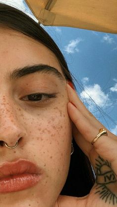 a woman with freckles and piercings on her nose