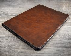 a brown leather notebook sitting on top of a wooden table