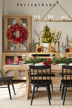 a dining room table decorated for christmas with candles and wreaths on the wall behind it