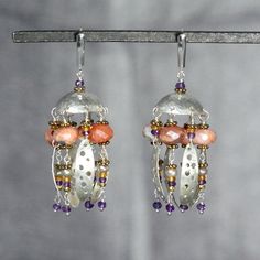 "Lovely, luscious dangle earrings. There are eight dangles that hang from a hammered half dome.  The dangles are composed of a strand featuring beautiful faceted fire opals, alternating with a strand featuring an organic hammered and pierced silver oval. There are additional accents of amethyst, pyrite, citrine gemstones, pearls, and gold beads.   This is a mixed metal piece with fine silver, sterling silver, and gold. Dimensions: Length from the top of the ear wire is 2 1/2\"\" (64 mm),  and 1 1/8\" (29 mm) at its widest point." Fusion Style Chandelier Earrings With Dangling Beads, Fusion Style Dangle Chandelier Earrings, Fusion Style Dangle Earrings For Jewelry Making, Unique Chandelier Drop Earrings With Dangling Beads, Artisan Dangle Chandelier Earrings For Pierced Ears, Artisan Chandelier Dangle Earrings For Pierced Ears, Fusion Dangle Metal Earrings, Artisan Dangle Chandelier Earrings, Sterling Silver Fusion Chandelier Dangle Earrings