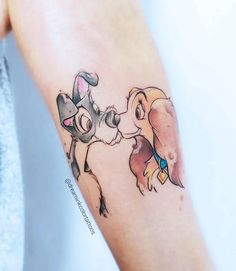 a lady and the tramp tattoo on the right arm with an elephant kissing her dog