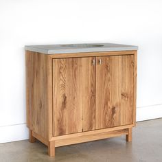 a wooden cabinet with two doors and a sink on the top, in front of a white wall