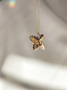 a gold necklace with a butterfly pendant hanging from it's side on a chain