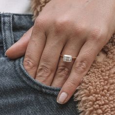 a close up of a person's hand with a ring on their finger and jeans