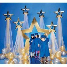 three children in graduation gowns standing under stars