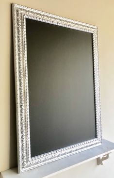 a white framed mirror sitting on top of a shelf