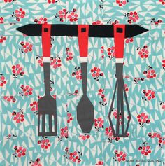 three kitchen utensils hanging on a wall with red flowers and blue tiles in the background