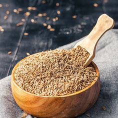 a wooden bowl filled with brown rice on top of a blue cloth