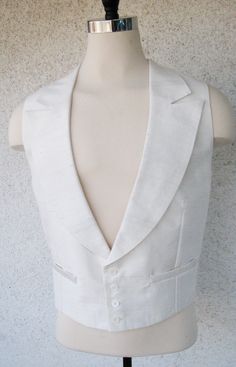 ABOUT THIS STYLE: A classic white tie suit straight out of the 1930s. This look features a formal tailcoat with silk-face grosgrain peak lapels, a pointed hemline, and curved tails. The outfit also features a white silk peak lapel vest and a custom formal pleated pant with a high waist. This style is famous for elongating the legs and creating the ultimate look of formal elegance. CUSTOM MADE: You can choose all of the details (tail shape, lapel shape, pant and cuff style) and fabrics (wools and White Fitted Suit And Tie Accessories For Formal Occasions, Elegant Tailored White Suit And Tie Accessories, Classic Three-piece Suit For Groom With Pressed Crease, Classic Single Button White Tuxedo, Classic Fitted Tuxedo With Lapel Collar, Classic Fitted Three-piece Suit For Black Tie Event, Fitted Classic Three-piece Suit For Black Tie Event, Classic Single Breasted Tuxedo For Wedding, Classic Flat Front Suits For Wedding