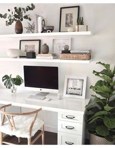 a white desk with a computer on it and some plants in front of the monitor