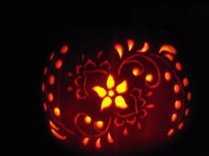 a carved pumpkin with an intricate design on it's face, lit up in the dark