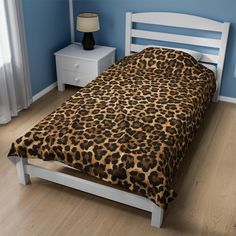 a bed with a leopard print comforter in a blue room next to a night stand