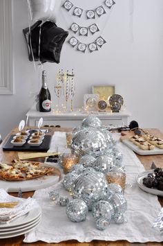 a table topped with lots of food next to balloons and confetti on top of plates