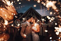 a newly married couple kissing while surrounded by sparklers