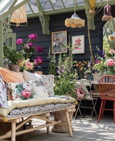 an outdoor seating area with lots of flowers on the table and chairs in front of it