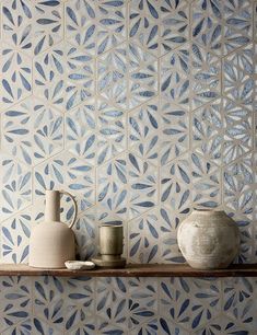 two vases are sitting on a shelf in front of a wall with blue and white tiles