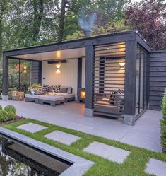 an outdoor living area with a couch and water feature in the foreground, surrounded by greenery