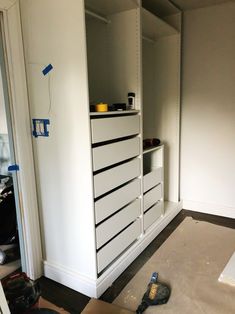 a white cabinet with drawers and tools on the floor in a room that is being remodeled