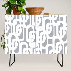 a potted plant sitting on top of a white cabinet next to a wooden bowl