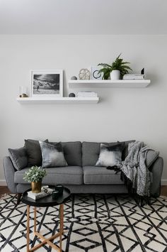 a living room with grey couches and black and white rugs on the floor