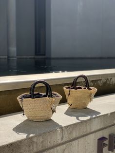 The Camille bag is our very modern version of the traditional Panier basket in a mini size. The basket, handmade by artisans in Spain in palm leaf straw, is covered in a metallic silver mesh, and the short handles coiled in black leather. It is lined in black cotton fabric, with leather drawstring with metal star charms. The bag is finished with a Cuckoo B keychain featuring a buffalo horn star made in Vietnam, a handmade in Argentina ceramic white star and the Cuckoo B bronze tag. It is inspire Black Cotton Fabric, Metal Star, Bag Silver, Metal Stars, White Star, Palm Leaf, Star Charms, Black Cotton, Straw Bag